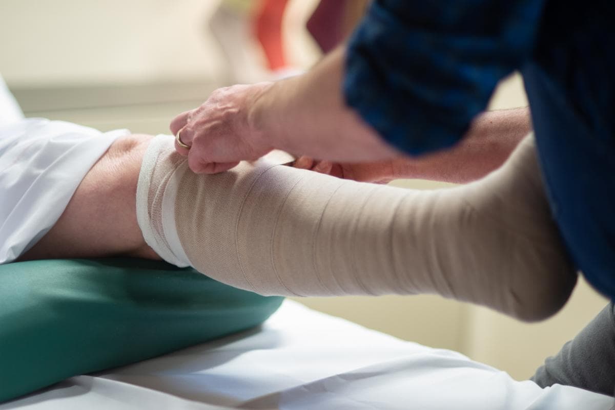 Lymphedema specialist applying customized compression bandage during intensive phase of CDT.