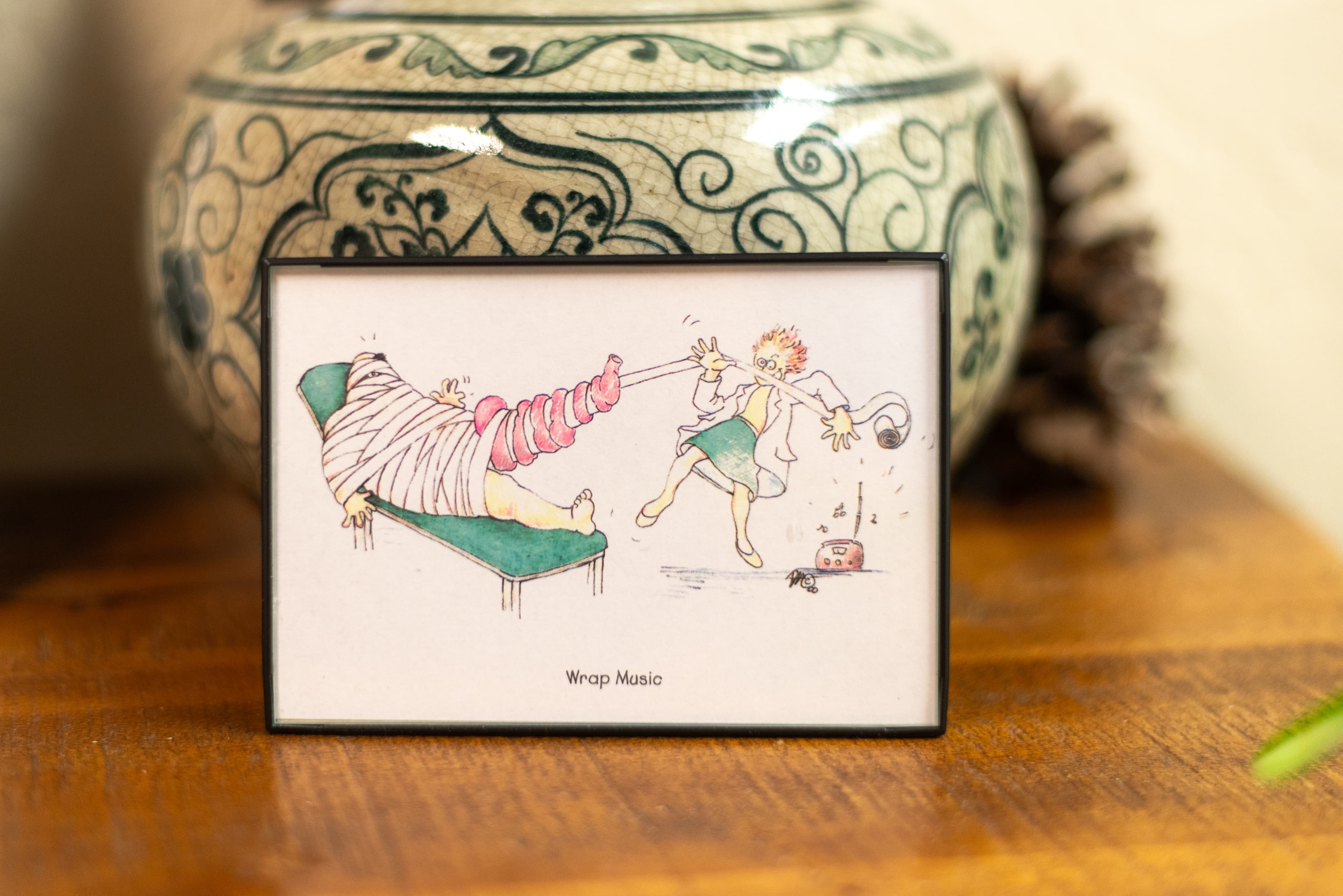 Photo of a framed comic depicting a practitioner emphatically wrapping a patient's bandages to music with the caption "Wrap Music"
