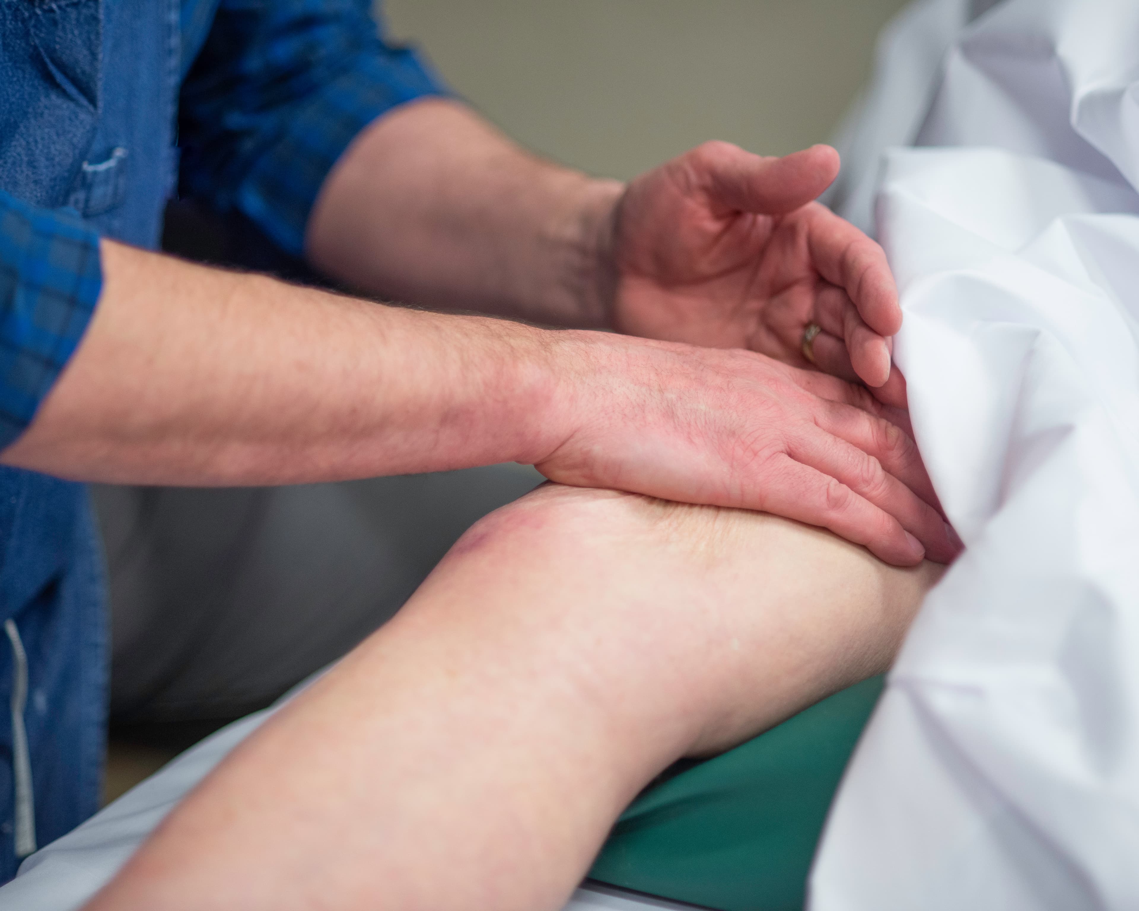 John massaging a patient's leg in one of the treatment rooms.