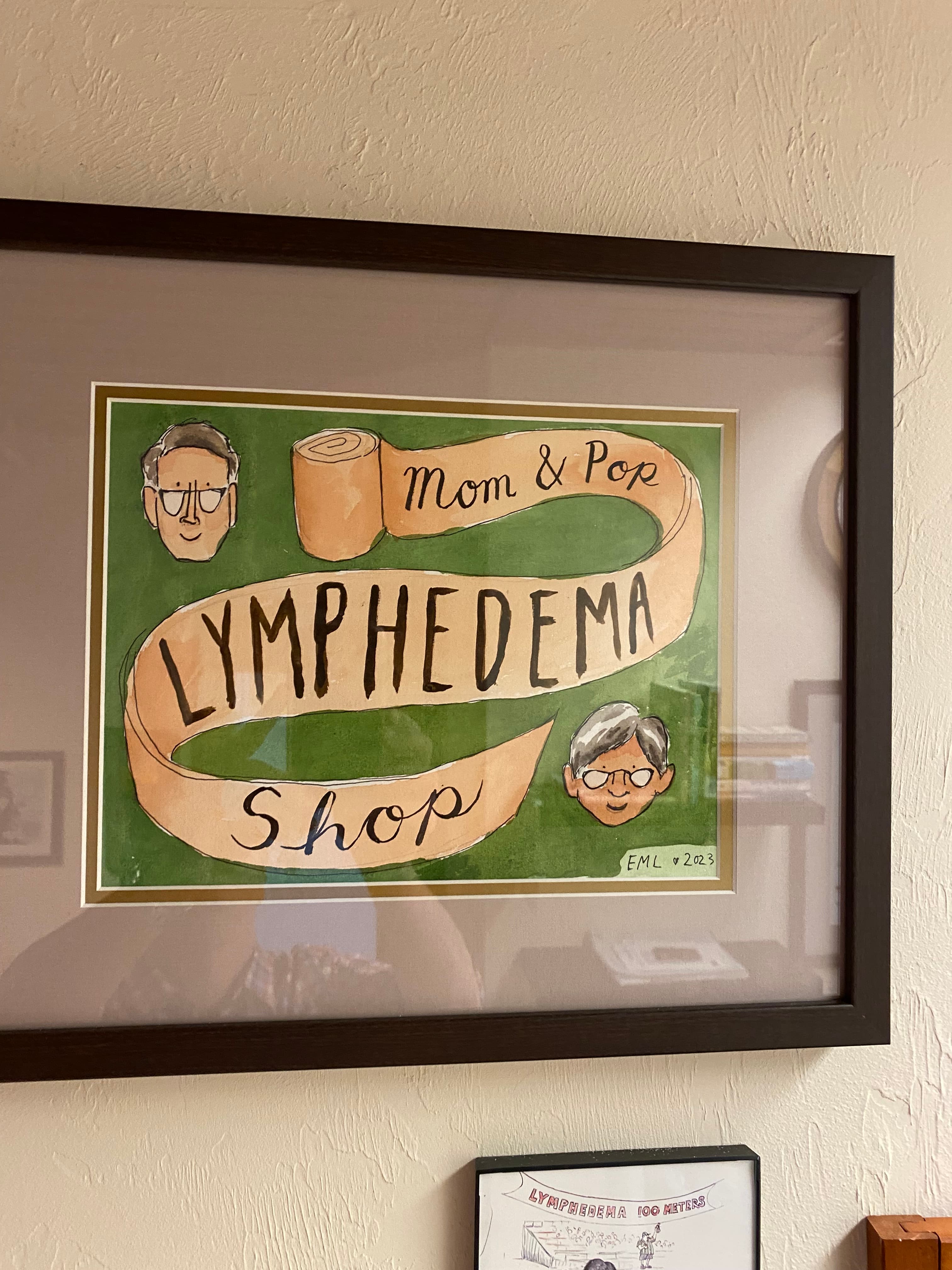 A framed illustration of John and Melissa with a bandage acting as a banner which says "Mom and Pop Lymphedema Shop."